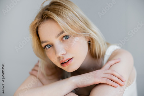 Portrait of young blonde woman looking at camera isolated on grey.