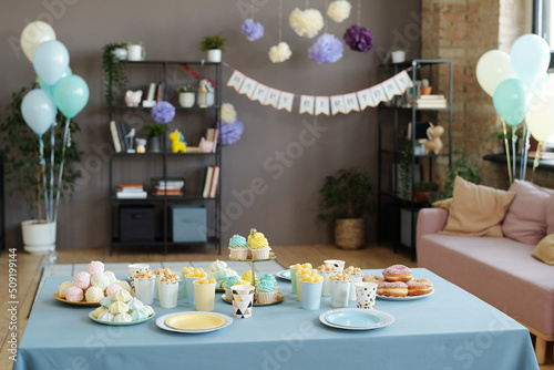 Image of holiday table served with desserts, cupcakes, donuts and other sweets preparing for birthday party at home photo