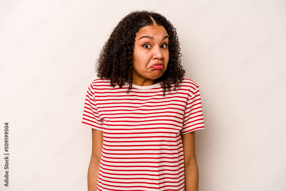 Young African American woman isolated on white background shrugs shoulders and open eyes confused.
