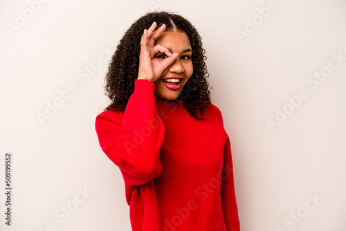 Young African American woman isolated on white background excited keeping ok gesture on eye. © Asier