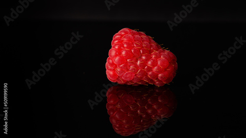 raspberry on black background with reflection on black bottom photo