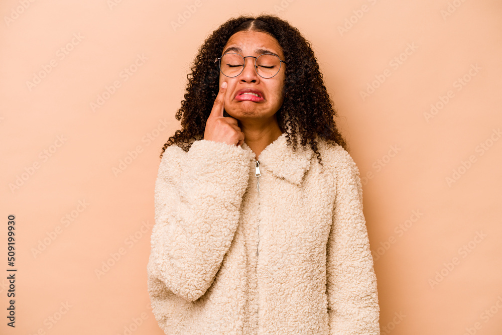 Young African American woman isolated on beige background crying, unhappy with something, agony and confusion concept. Young African American woman isolated on beige background crying, unhappy with something, agony and confusion concept.
