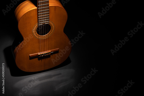 Classical guitar body on a dark grey surface with black copy space
