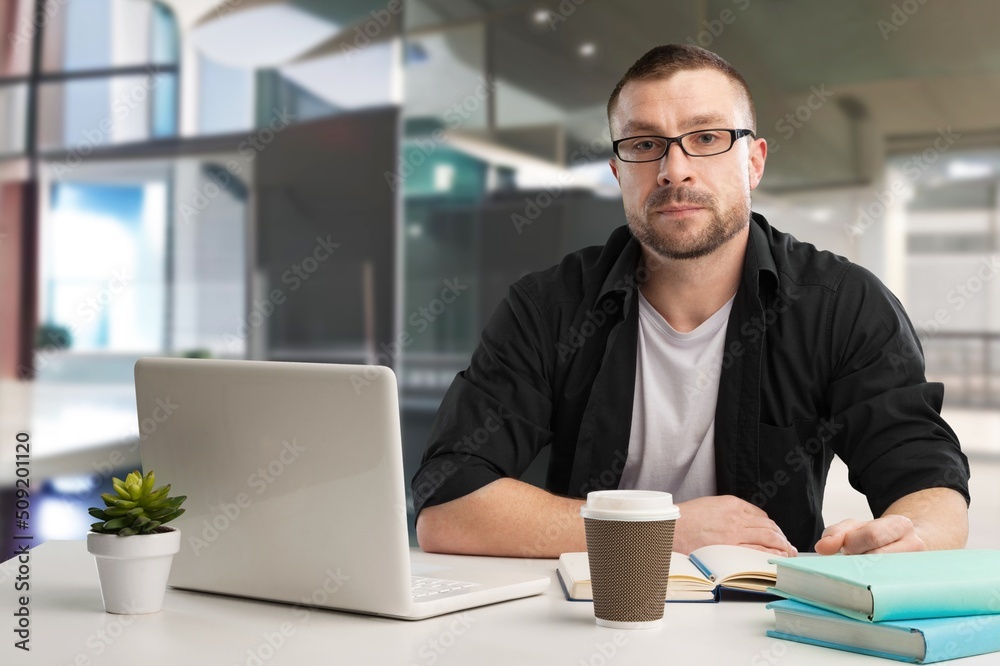 Busy Young Businessman Using Computer in Modern Office. Manager Thinks About Successful Financial Ideas. Busy Young Businessman Using Computer in Modern Office. Manager Thinks About Successful Financial Ideas.
