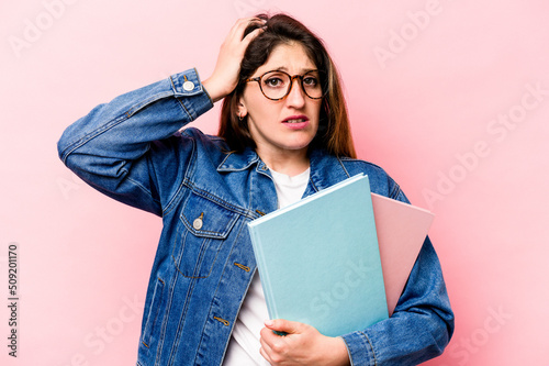 Young student caucasian woman isolated on pink background being shocked, she has remembered important meeting.