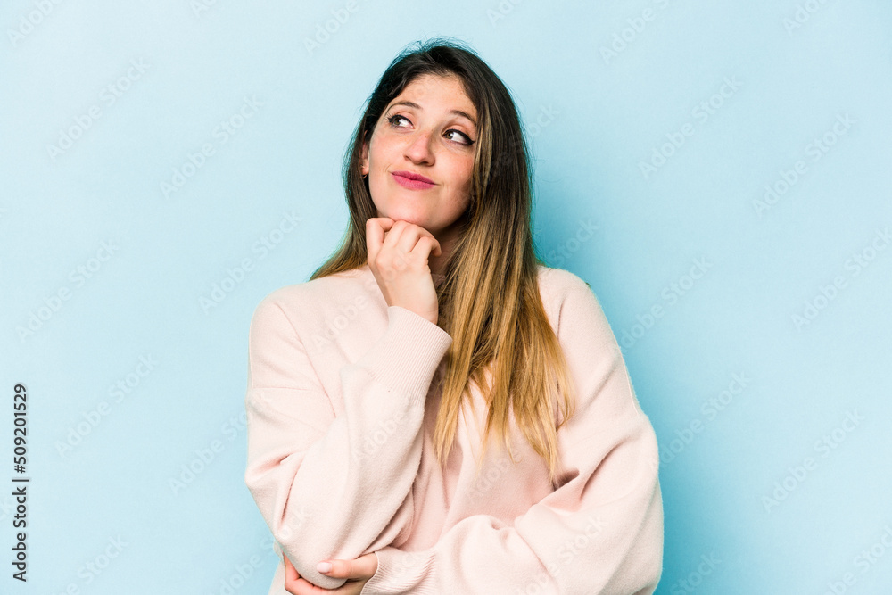Young caucasian woman isolated on blue background thinking and looking up, being reflective, contemplating, having a fantasy. Young caucasian woman isolated on blue background thinking and looking up, being reflective, contemplating, having a fantasy.