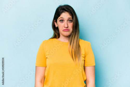 Young caucasian woman isolated on blue background sad, serious face, feeling miserable and displeased.