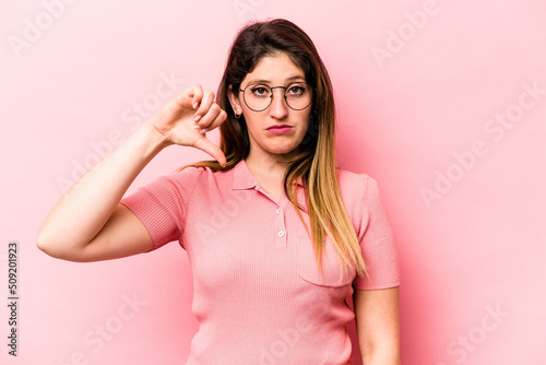 Young caucasian woman isolated on pink background showing a dislike gesture, thumbs down. Disagreement concept.