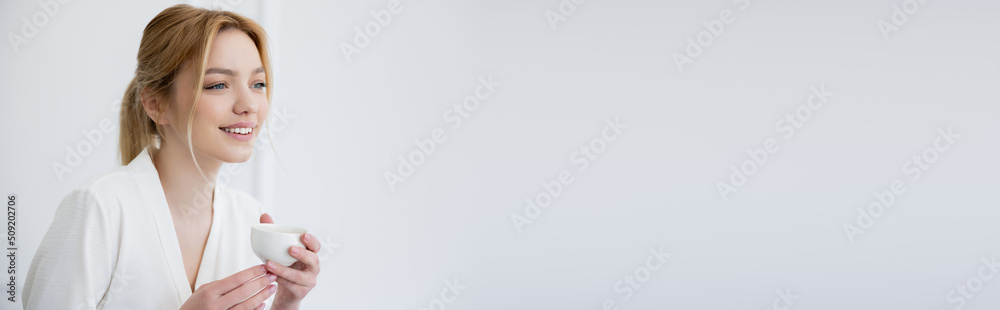 Happy blonde woman holding cup of coffee at home, banner.