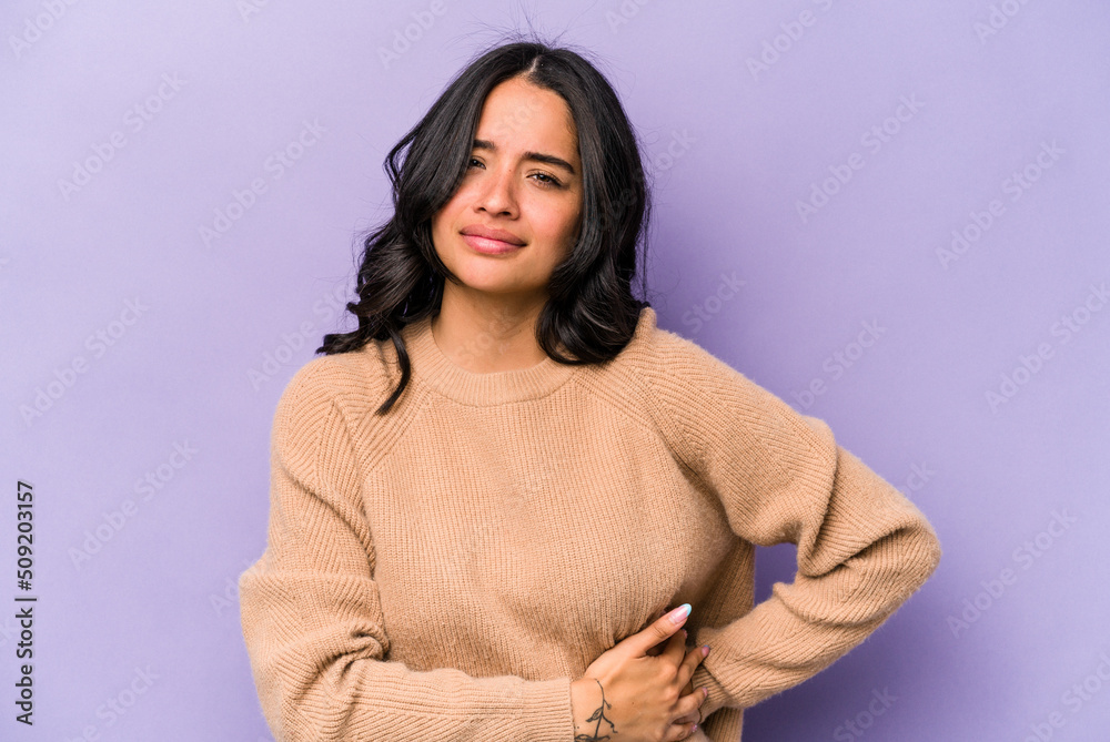Young hispanic woman isolated on purple background having a liver pain, stomach ache. Young hispanic woman isolated on purple background having a liver pain, stomach ache.