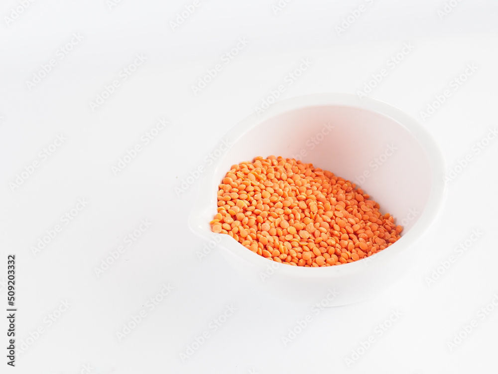 Red lentils in a white bowl on a white background. Red lentils macro Red lentils in a white bowl on a white background. Red lentils macro