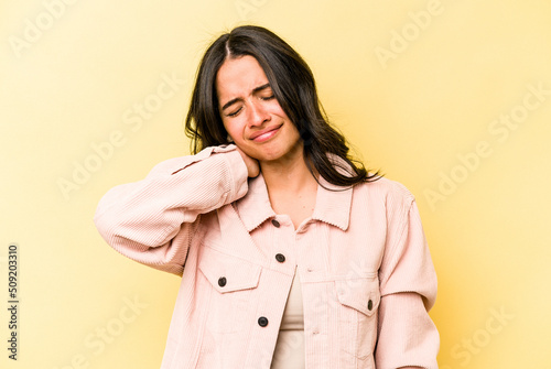 Young hispanic woman isolated on yellow background suffering neck pain due to sedentary lifestyle.