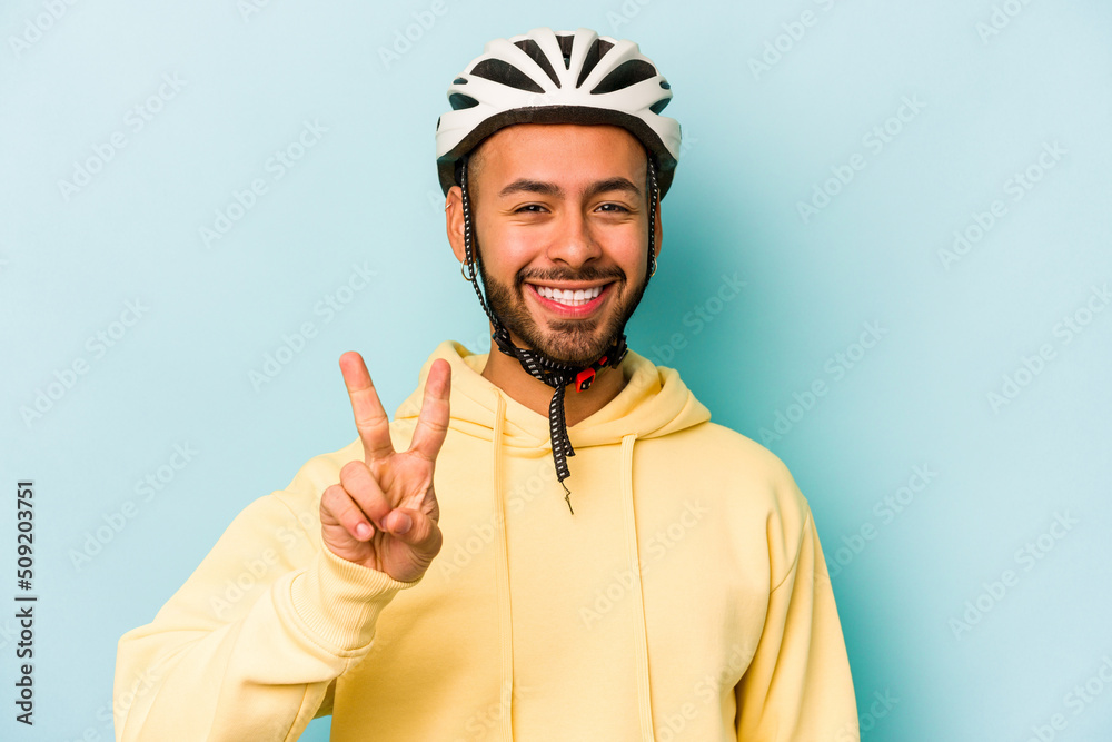Young hispanic man wearing helmet isolated on blue background showing number two with fingers. Young hispanic man wearing helmet isolated on blue background showing number two with fingers.