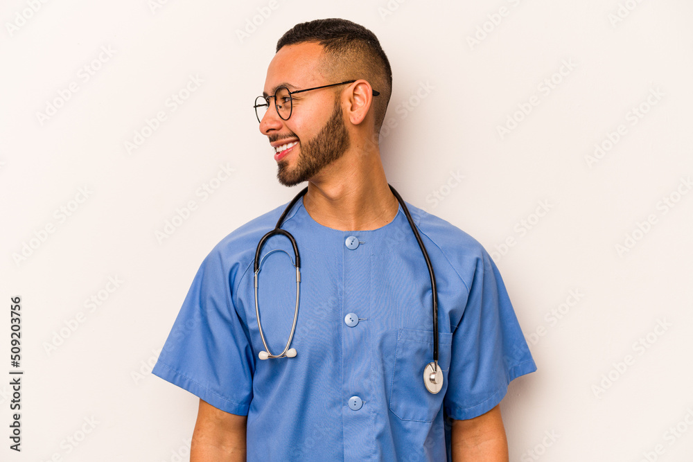 Young hispanic nurse man isolated on white background looks aside smiling, cheerful and pleasant. Young hispanic nurse man isolated on white background looks aside smiling, cheerful and pleasant.