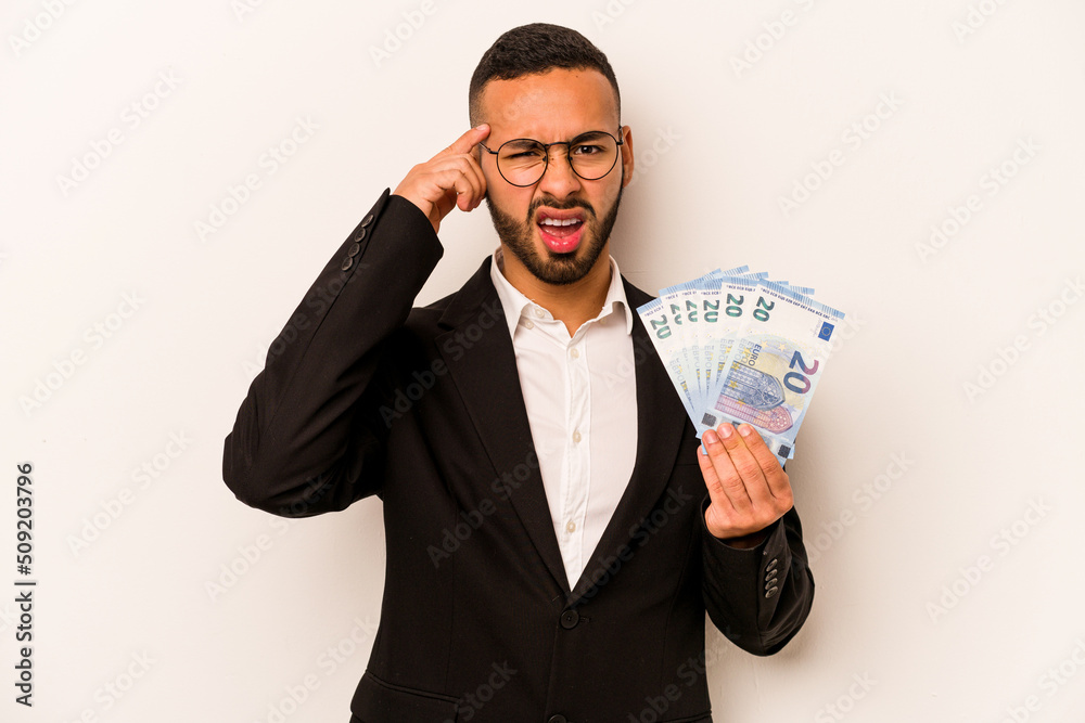 Young business hispanic man holding banknotes isolated on white background showing a disappointment gesture with forefinger. Young business hispanic man holding banknotes isolated on white background showing a disappointment gesture with forefinger.