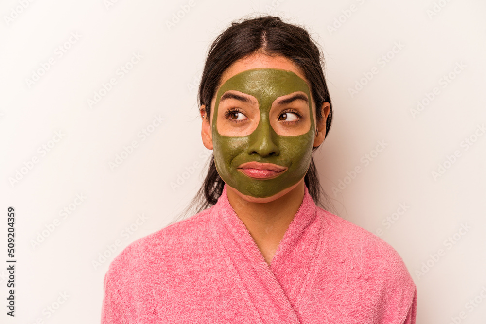 Young hispanic woman wearing a facial mask isolated on white background confused, feels doubtful and unsure. Young hispanic woman wearing a facial mask isolated on white background confused, feels doubtful and unsure.