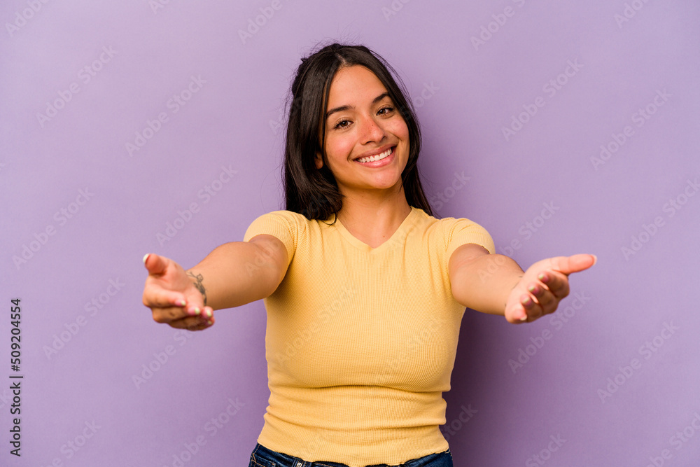 Young hispanic woman isolated on purple background showing a welcome expression.