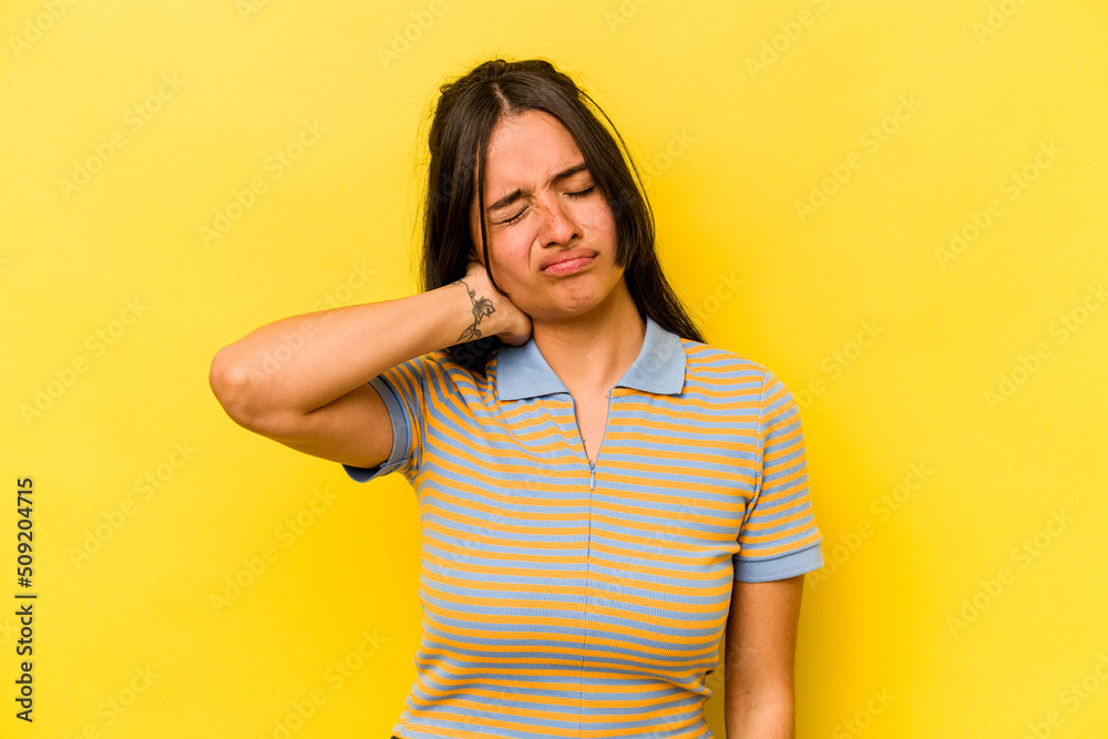Young hispanic woman isolated on yellow background having a neck pain due to stress, massaging and touching it with hand. Young hispanic woman isolated on yellow background having a neck pain due to stress, massaging and touching it with hand.