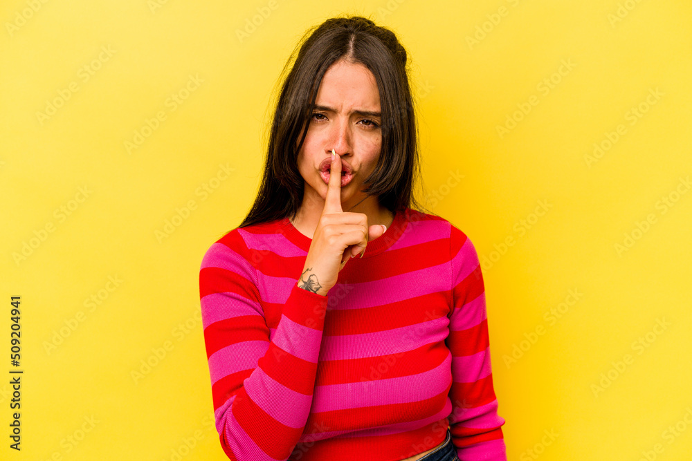 Young hispanic woman isolated on yellow background keeping a secret or asking for silence. Young hispanic woman isolated on yellow background keeping a secret or asking for silence.
