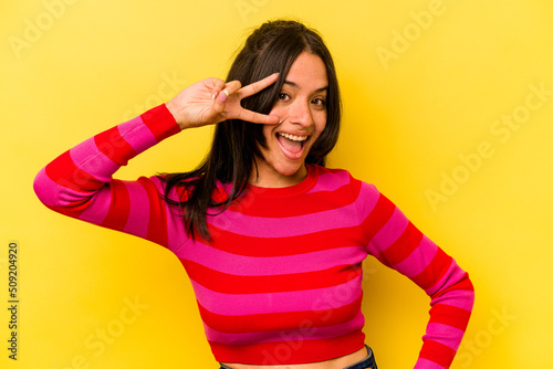 Young hispanic woman isolated on yellow background dancing and having fun.