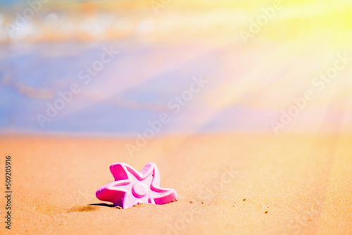 Beach sand castle with children's toy in sun rayses as symbol of trawel, summer holiday and rest. Copy space for design. Horizontal image. photo