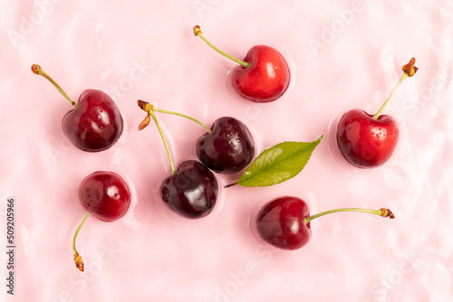 Obraz na plátně Fresh sweet cherry in pink calm water with splashes and waves.