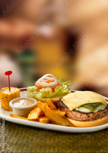 Hamburguesa abierta con queso, patatas y maíz. Open hamburger with cheese, potatoes and corn.