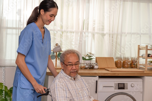 A young asian nurse hold a senior wheelchair at retired nursing home service.