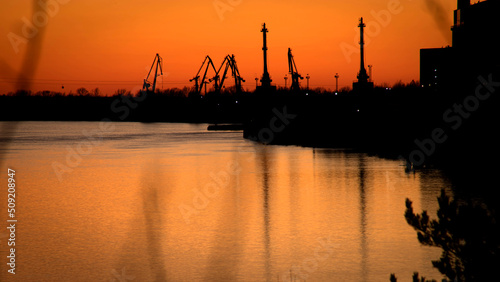 Sunset on the Volga river. Silhouettes of port cranes on the river bank. Views Of the river port of Bor. April 2022.