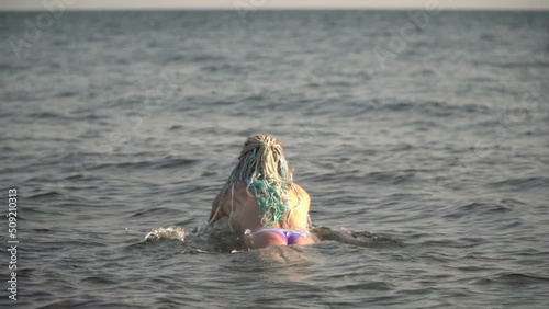 Young sexy woman in bikini dives into the sea. Hot beautiful woman swims in the water