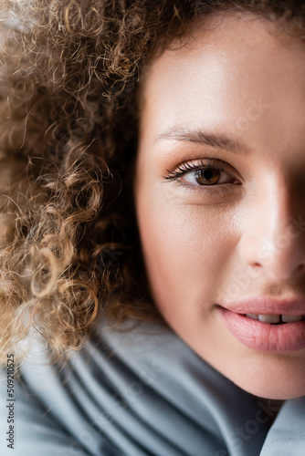 cropped view of smiling woman with curly hair looking at camera.