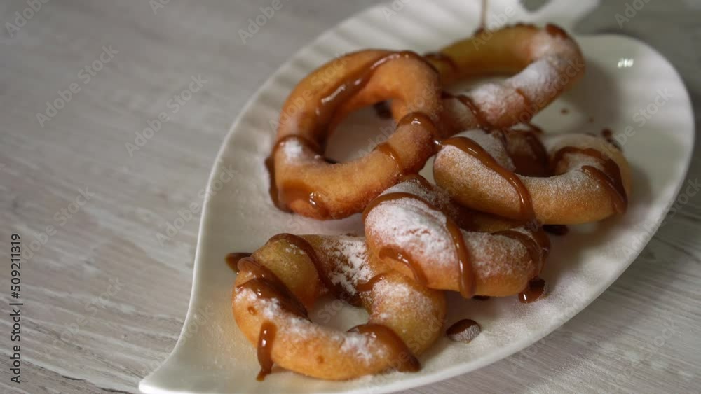 Close up of caramel sauce pouring over sweet doughnuts in plate. Sweet dessert preparation Close up of caramel sauce pouring over sweet doughnuts in plate. Sweet dessert preparation