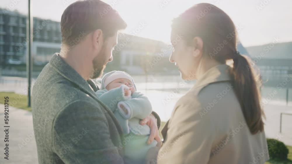 At sunset father and mother holding new born baby in hands and playing together. Smiling feel happy. Outdoors on street. Slow motion At sunset father and mother holding new born baby in hands and playing together. Smiling feel happy. Outdoors on street. Slow motion