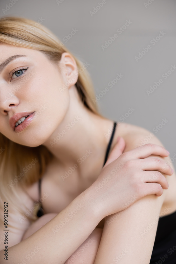 Cropped view of blonde woman looking at camera isolated on grey. Cropped view of blonde woman looking at camera isolated on grey.