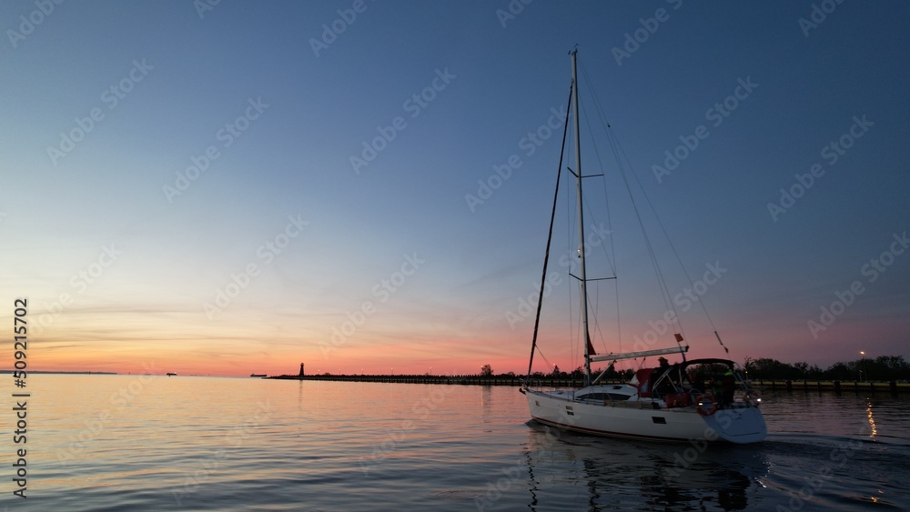 Sailing yacht on the background of the fiery sunset of the Baltic Sea.