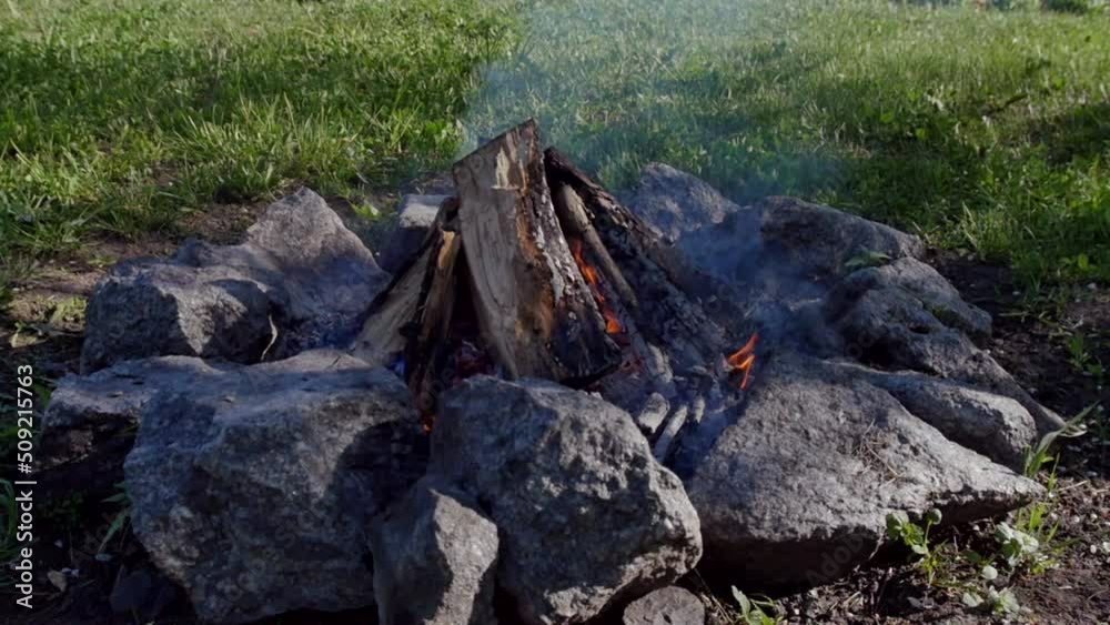 The hearth in the garden is fenced with stones, on a background of green lawn and garden. slow motion The hearth in the garden is fenced with stones, on a background of green lawn and garden. slow motion