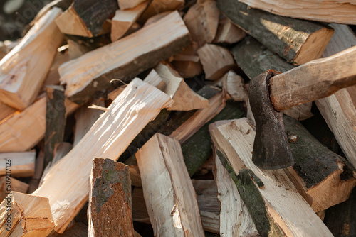 The ax sticks out in a log on a pile of firewood for the stove. Agriculture