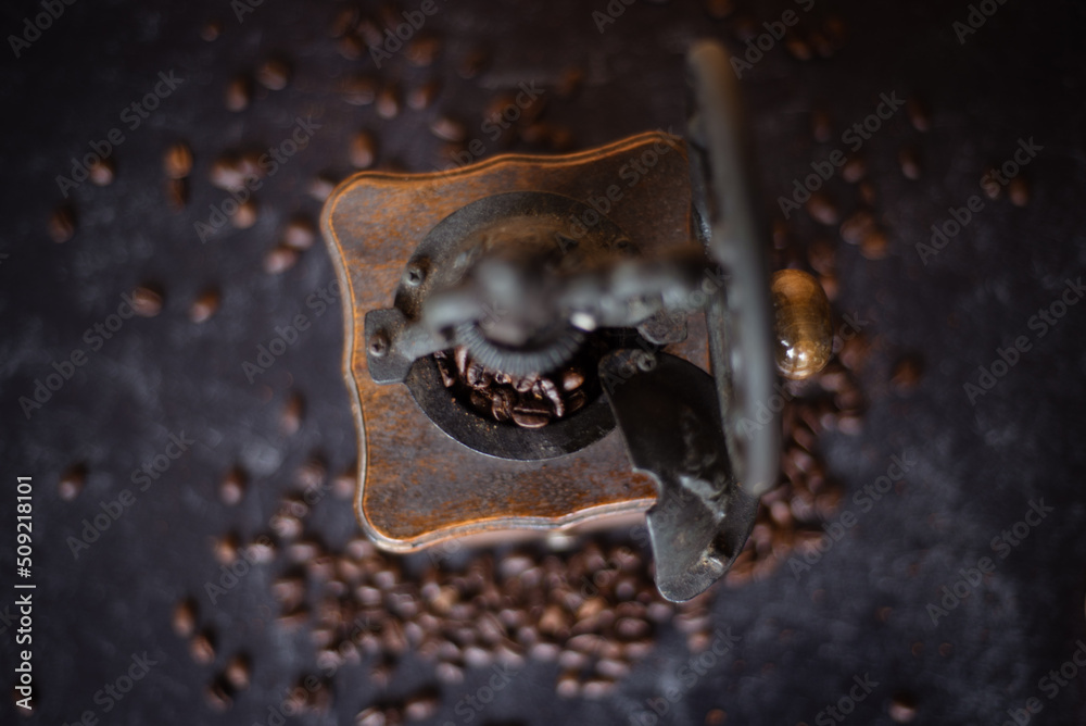 Top view of a vintage coffee grinder with beans on dark black concrete background. Depth of field. Wood and iron.