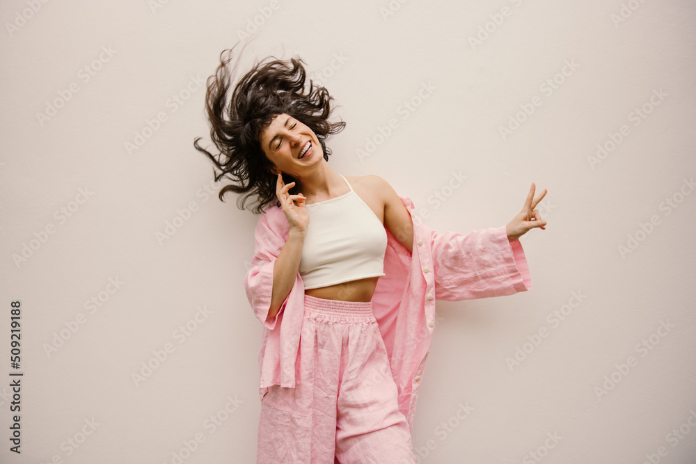 Funny young caucasian girl closing her eyes has fun waving hair on white background. Brunette wears summer casual clothes. Leisure lifestyle and beauty concept. Funny young caucasian girl closing her eyes has fun waving hair on white background. Brunette wears summer casual clothes. Leisure lifestyle and beauty concept.