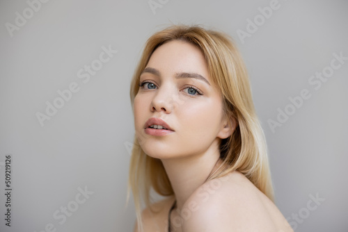 Portrait of young blonde woman looking at camera isolated on grey.