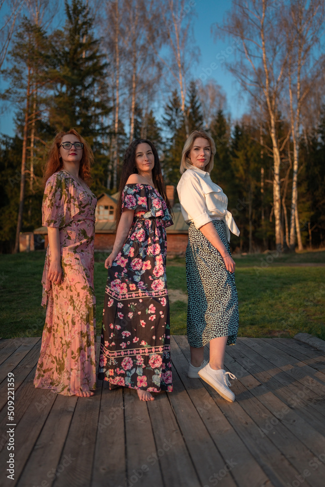 Naklejka premium Three girls girlfriends pose at the forest recreation center.