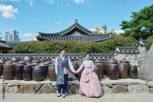 Fotografering 한국의 전통 가옥의 장독대를 배경으로 손잡거나 인사를 하는 젊은 아시아 한국 남녀 모델