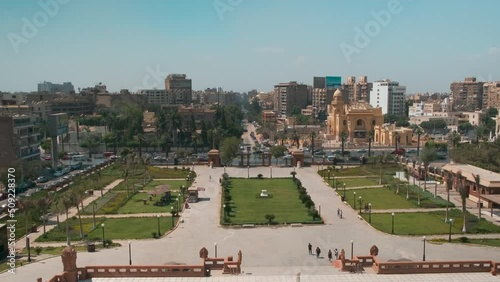 Heliopolis Cairo , Egypt from the top of Baron Empain Palace zooming and panning shot in daylight showing the palace garden, El-Orouba street with cars and people moving photo