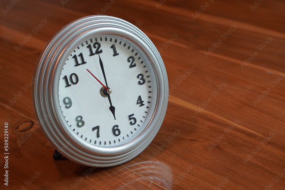 beautiful alarm clock, silver and white, placed on a wooden floor background, object, fashion,comfortable, modern, copy space