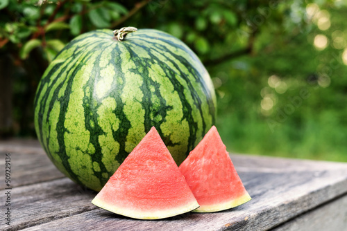 Fotografija Summer berry, ripe watermelon and slices on a wooden table outdoors, copy space