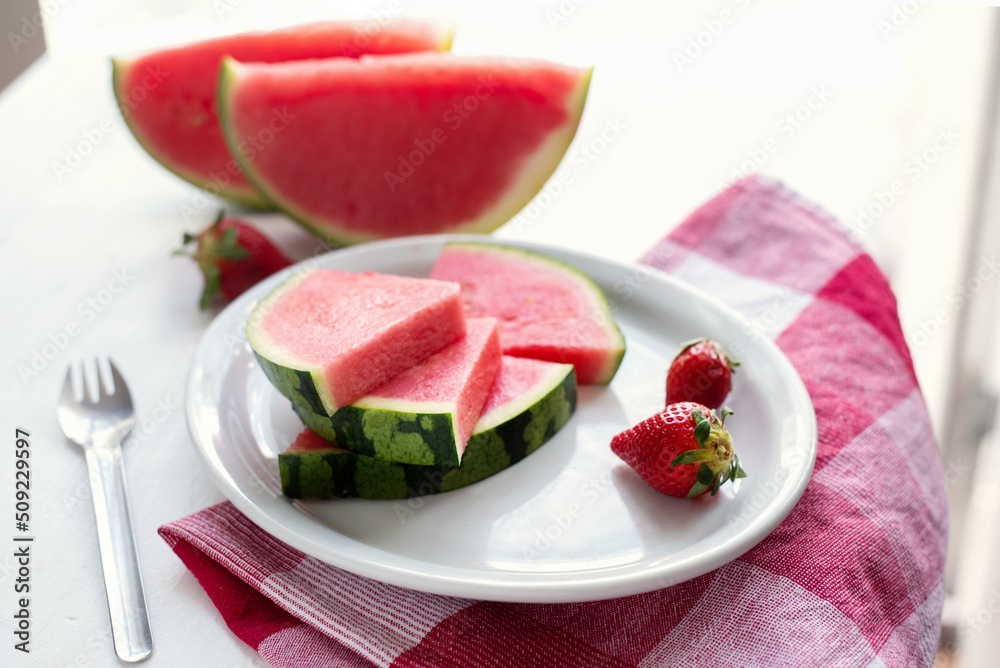 Watermelon slices and strawberries on a plate on a white table. Watermelon slices and strawberries on a plate on a white table.