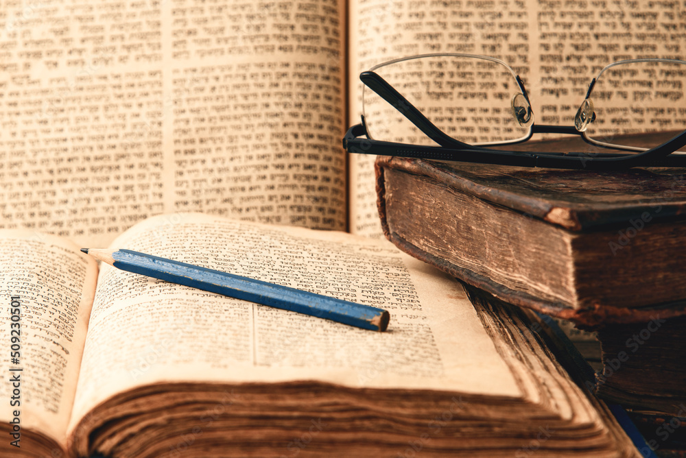 Old worn shabby jewish books, open pages of machzor and siddur. Reading Torah. Closeup. Selective focus.