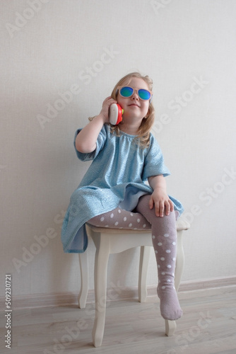 Obraz na płótnie girl in sunglasses playing with a toy phone