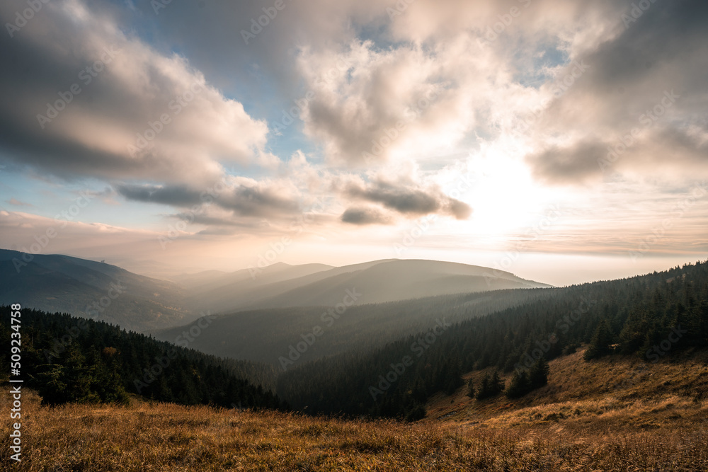 Fototapeta premium Landscape of warm light sun rays on sky through the clouds over the mountains in Czech republic, Jeseniky
