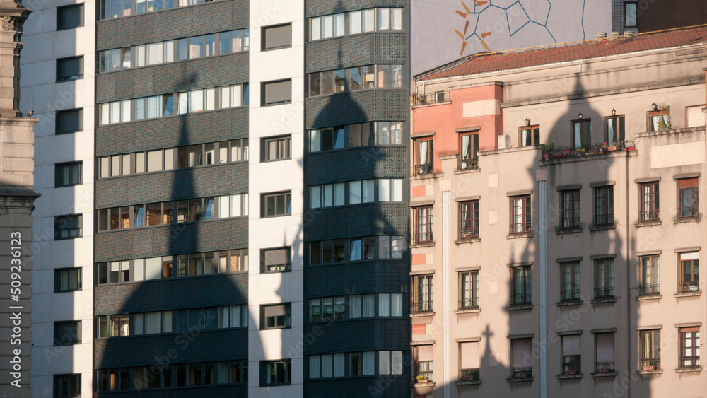 Sombras de torres de iglesia en fachadas de edificios urbanos